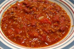 A bowl of chili with ground beef and tomatoes.