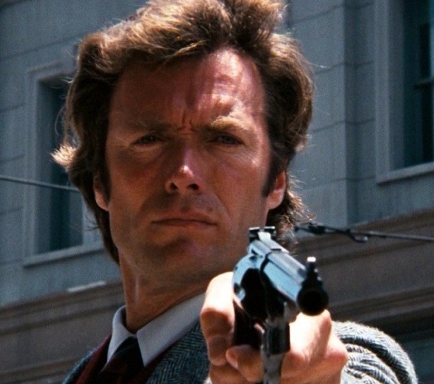 A man holding a gun in front of a building.