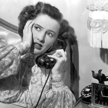 A woman is talking on the phone in front of a mirror.