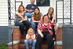 A family sitting on the steps of their home.