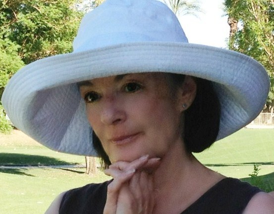 A woman wearing a white hat and posing for the camera.